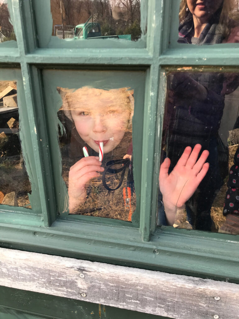 little boy with a candy cane peering through a window