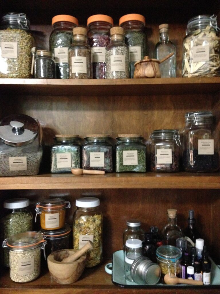 a cabinet with labeled jars of herbs