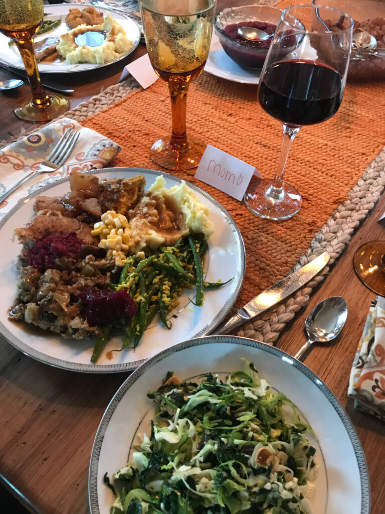 thanksgiving dinner on an orange table cloth with a glass of wine