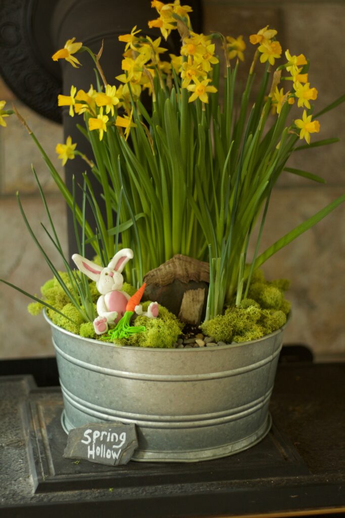 spring decor of daffodils and a clay bunny decoration in a silver pot
