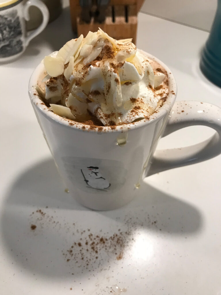 a snowman mug filled with hot chocolate and topped with whipped cream