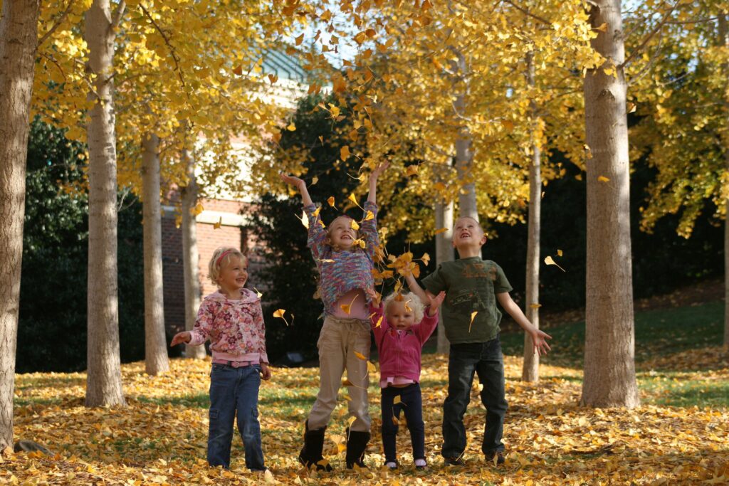 kids throwing up yellow fall leaves