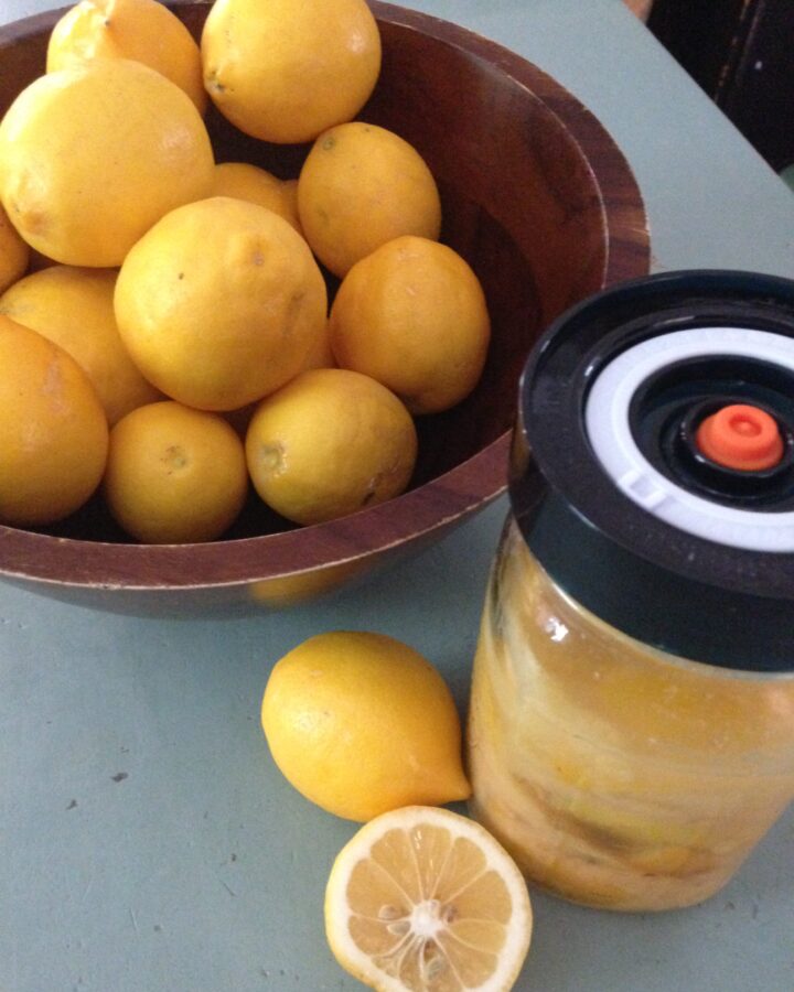 bowl of lemons with a jar of preserved lemons on the side