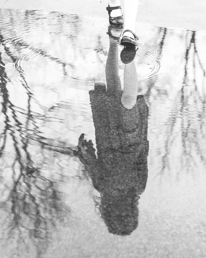reflection of a girl upside-down in a puddle