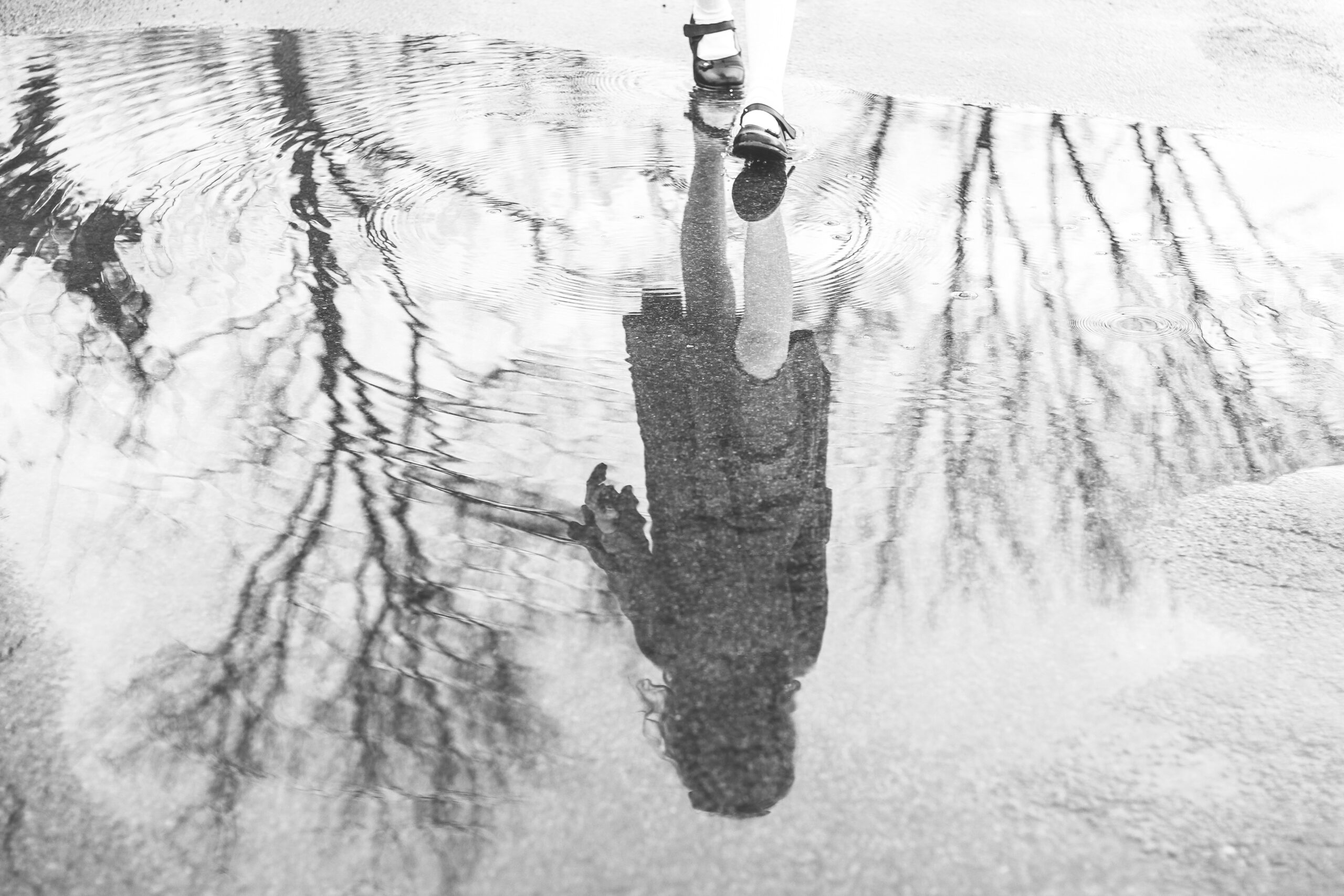 reflection of a girl upside-down in a puddle