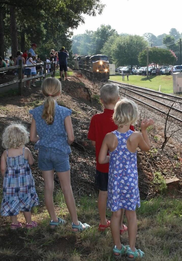 4 children watching a train come down the tracks
