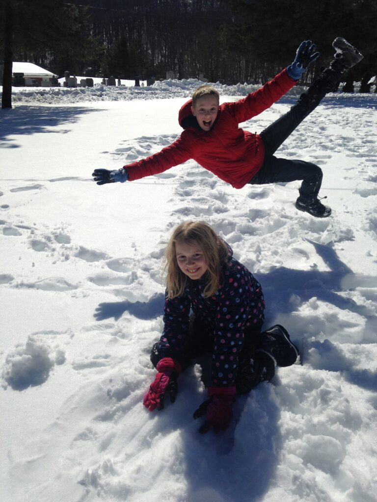 boy photo bombing girl posing for picture in the snow.
