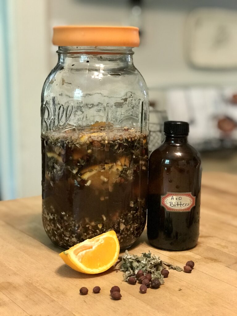 a jar of herbs steeping in vinegar with an orange slice and a jar