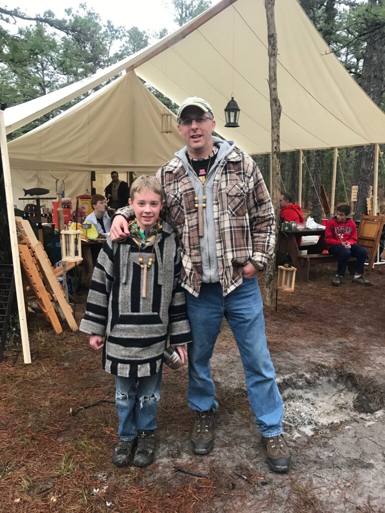 father and son in front of a canvas tent