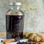 a jar of elderberry syrup with ginger and cinnamon sticks