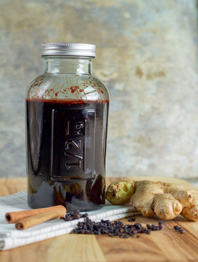 a jar of elderberry syrup with ginger and cinnamon sticks