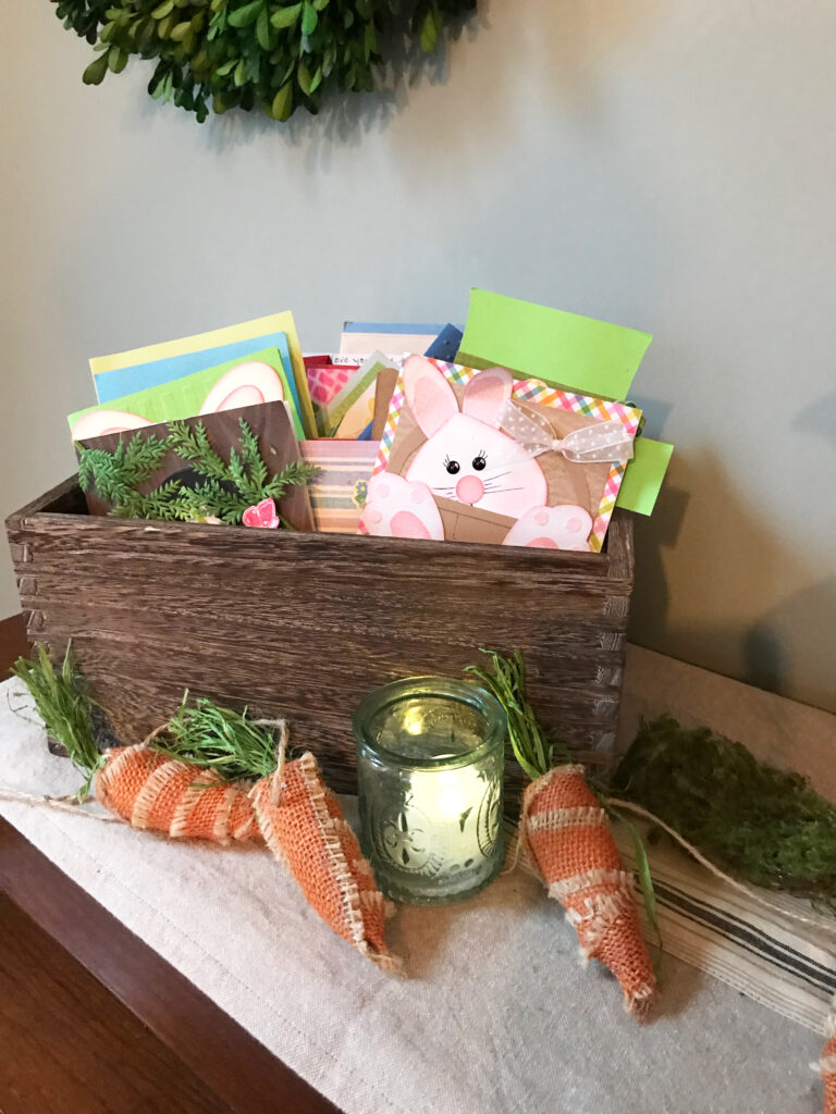 box filled with easter cards, a candle, and carrots