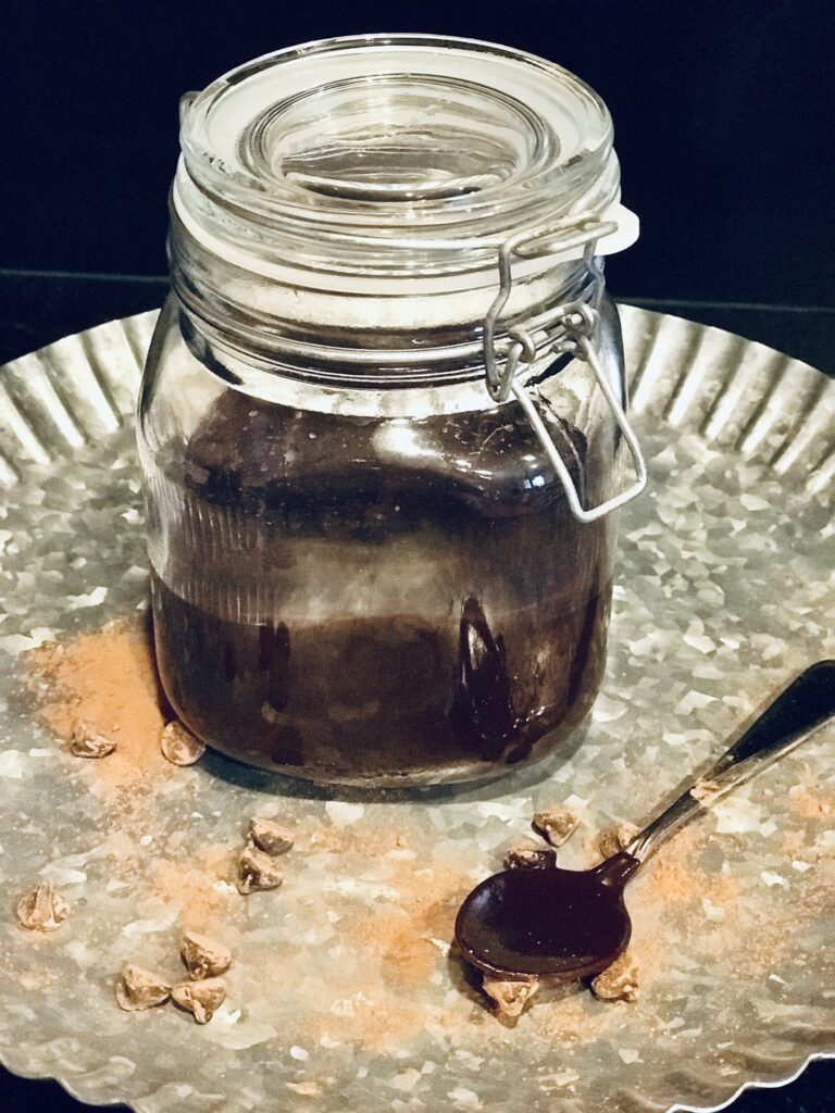 hot fudge sauce on a tin background with a spoon dipped in sauce