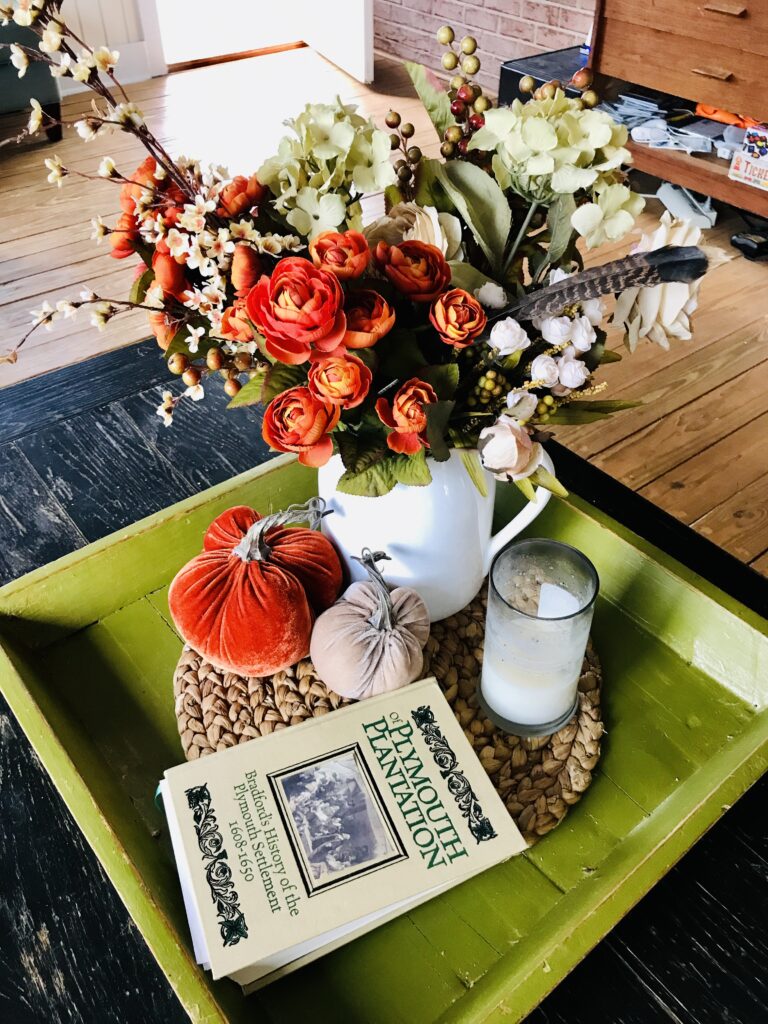 green tray with book, candle, velvet pumpkins and flowers