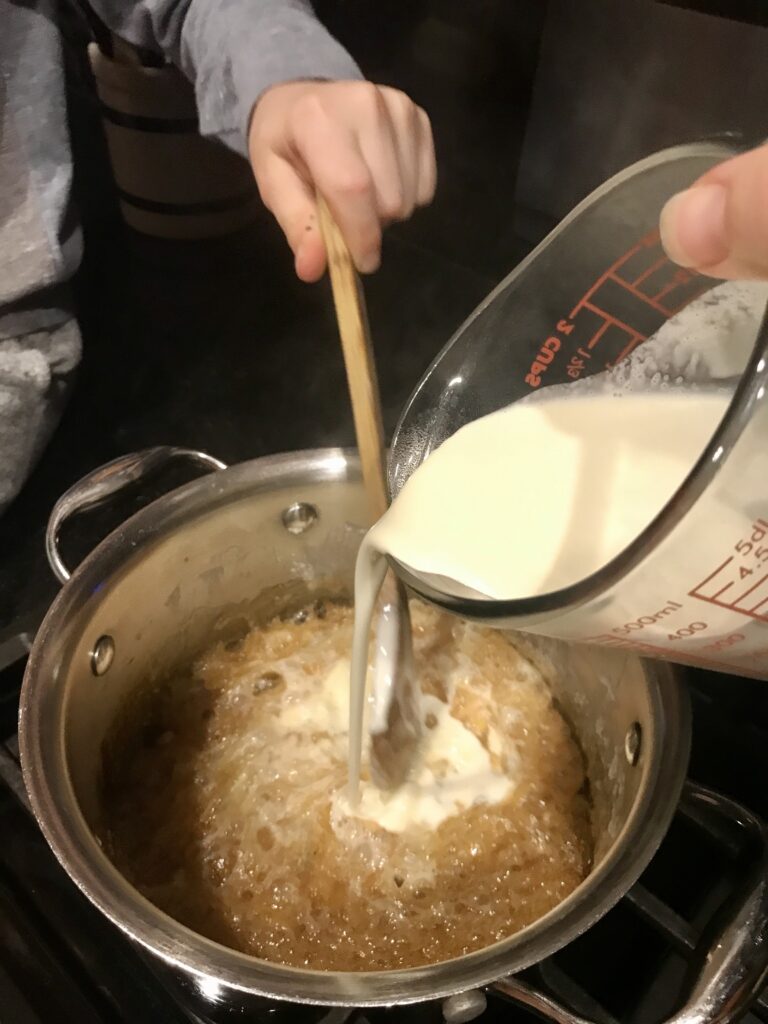 pouring cream into boiling caramel