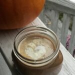 a jar of caramel sauce next to a pumpkin