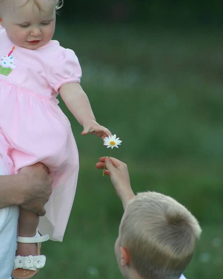 brother handing his little sister a flower