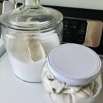 a jar of laundry detergent and dryer sheets on a washing machine