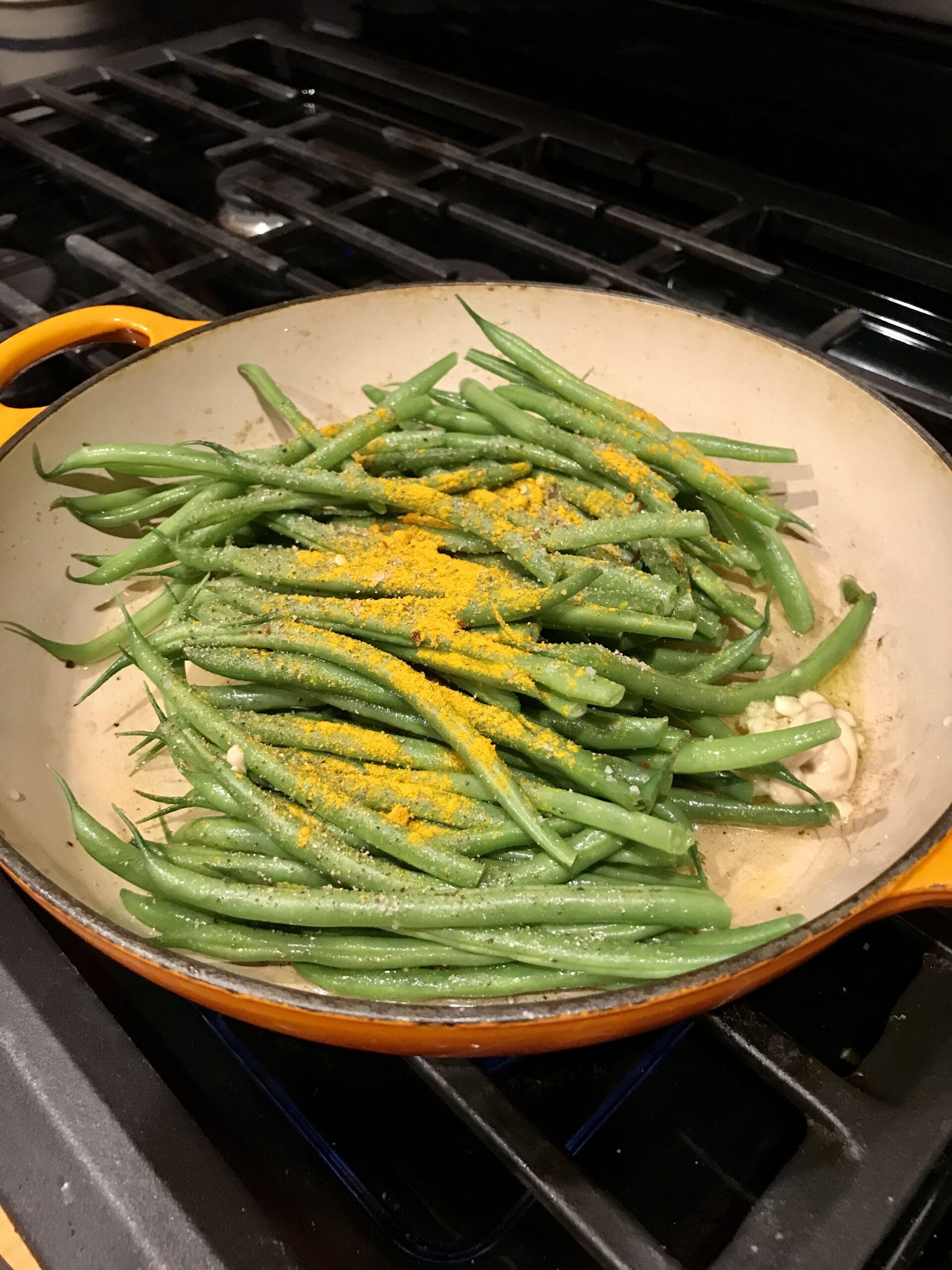 adding all the ingredients to an orange pan for coconut green beans