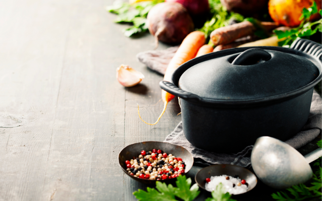 a cast iron pot surrounded by vegetables and spices