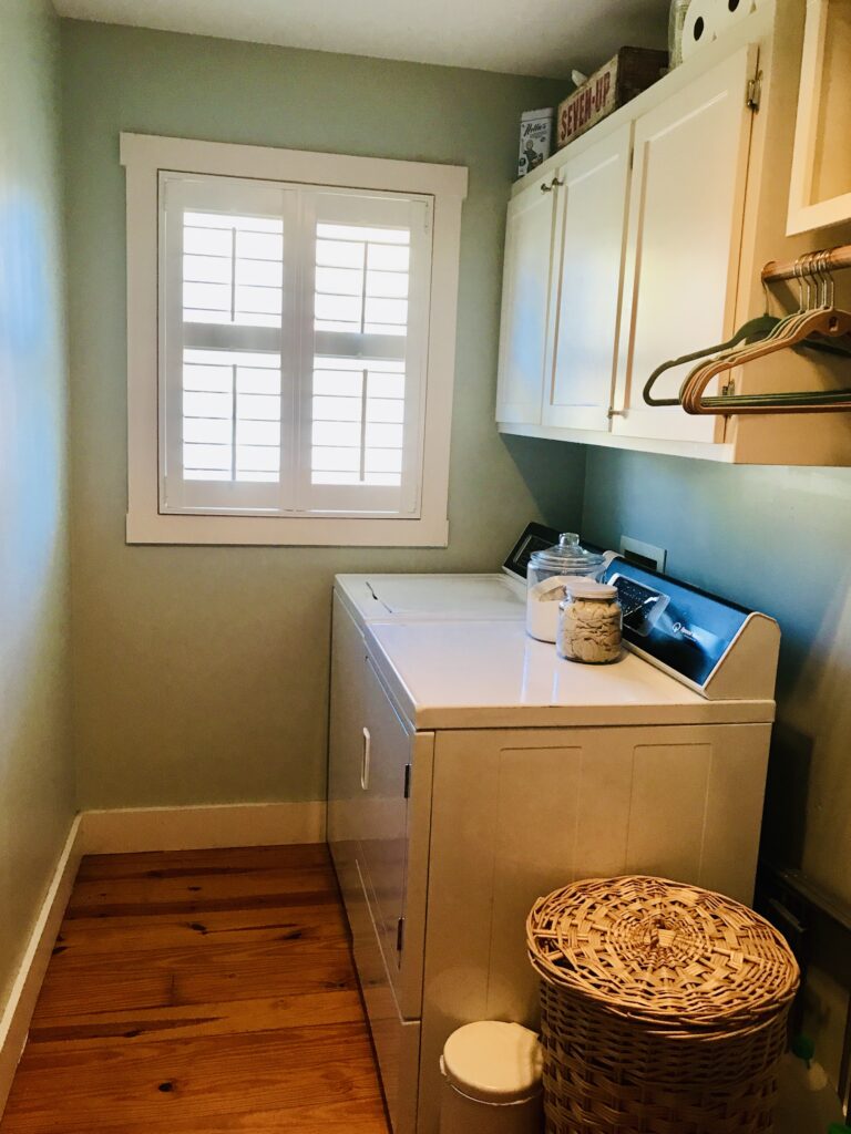 a laundry room with washer, dryer, window, laundry basket and hangers