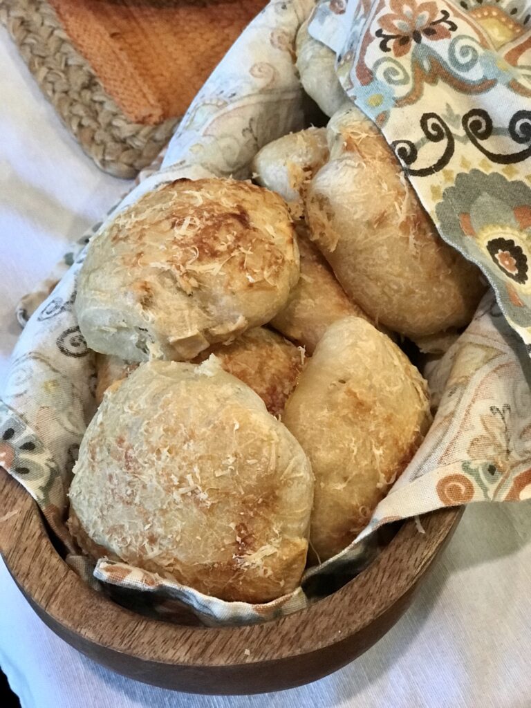 wood basket lined with a napkin filled with sourdough apple and rosemary dinner rolls