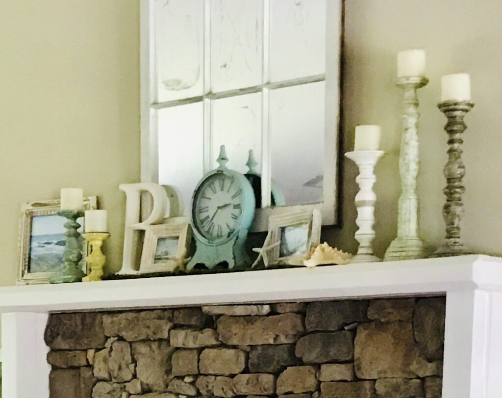 a fireplace mantle with a clock, mirror, and candles