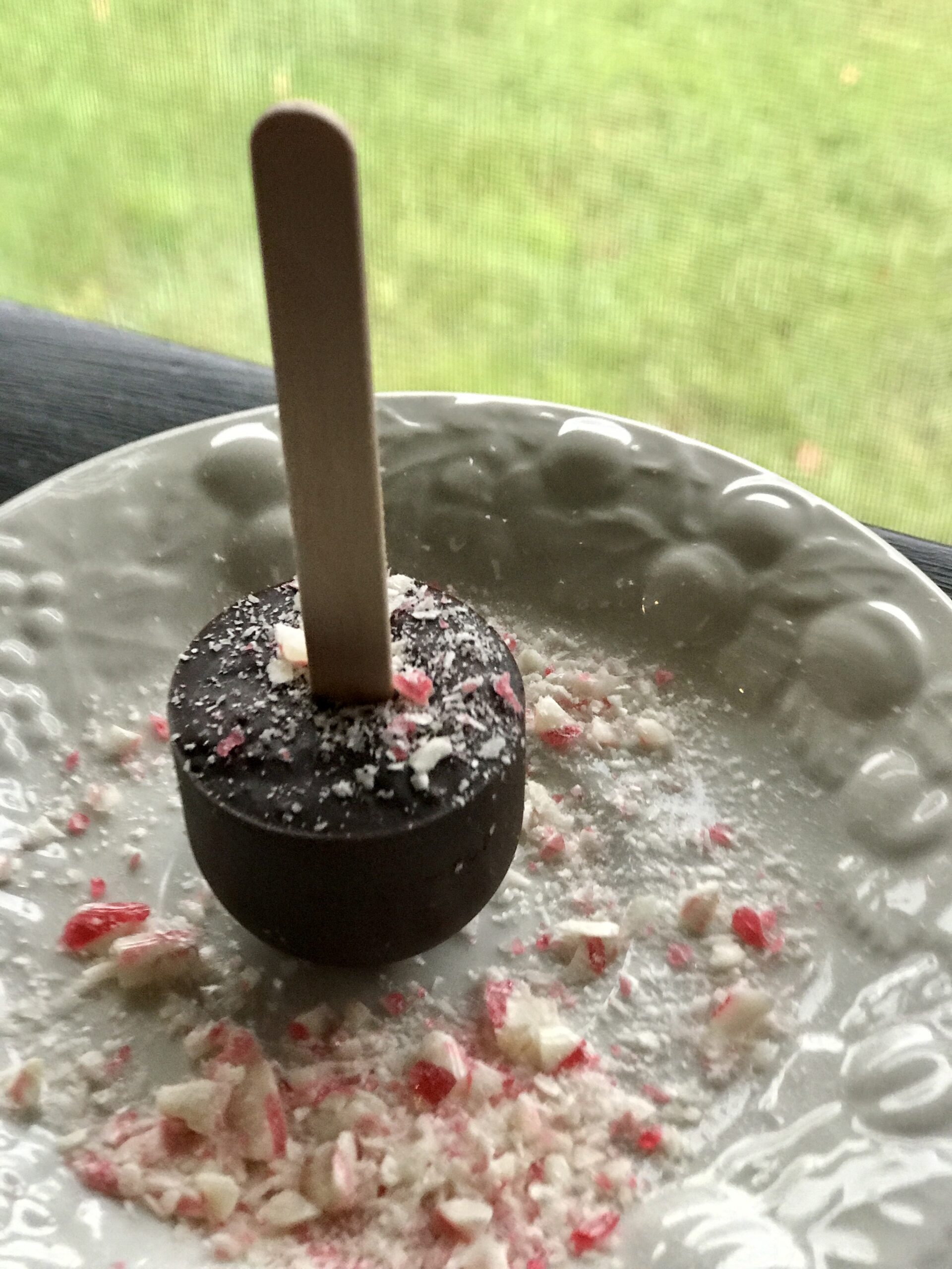 up close of hot chocolate on a stick on a plate with peppermint