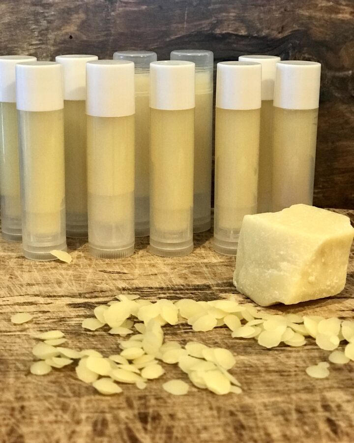tubes of lip balm with wax and cocoa butter on wood