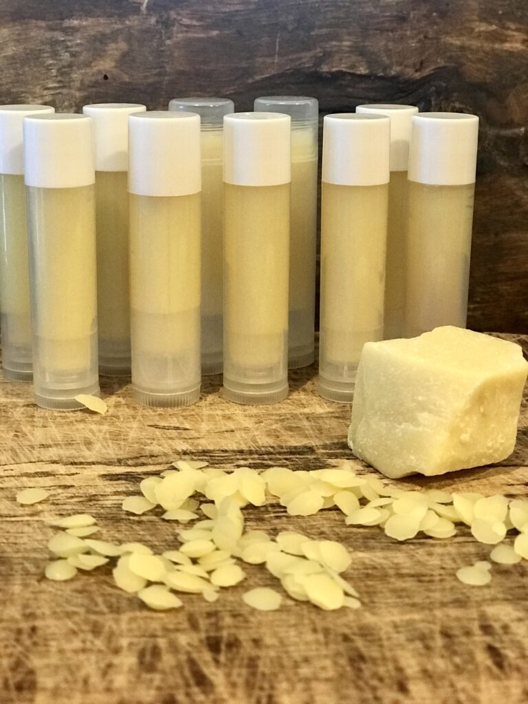 tubes of lip balm with wax and cocoa butter on wood