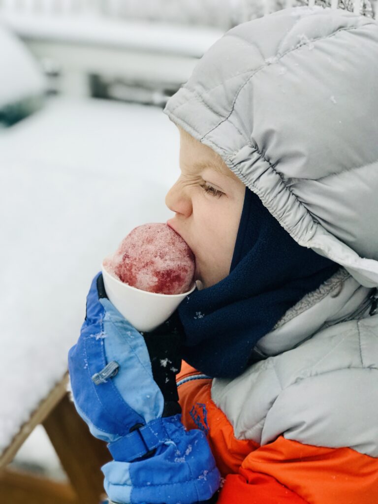 boy eating a winter citrus and pine shrub snow cone