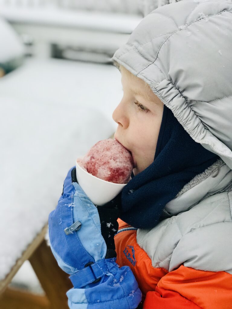 boy eating a winter citrus and pine shrub snow cone