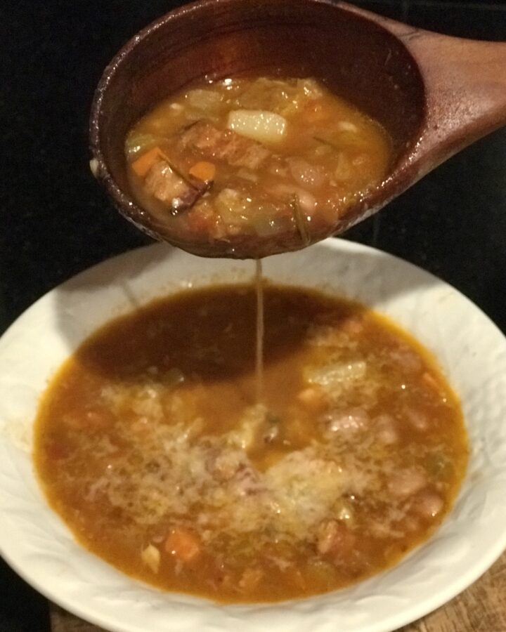 a bowl of bean & farro soup with bacon being labeled into a bowl