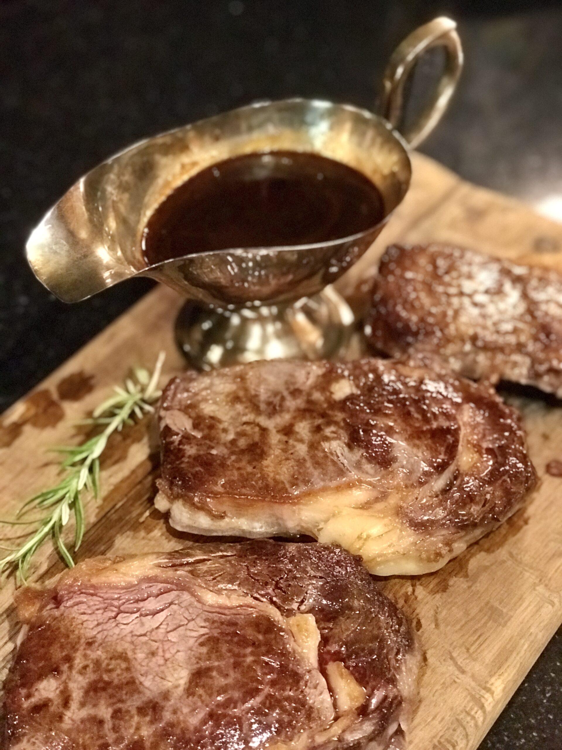 3 steaks on a breadboard with pan sauce