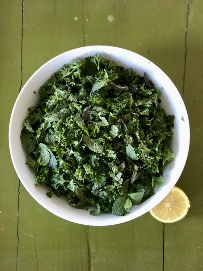 white bowl of parsley mint salad on a green background