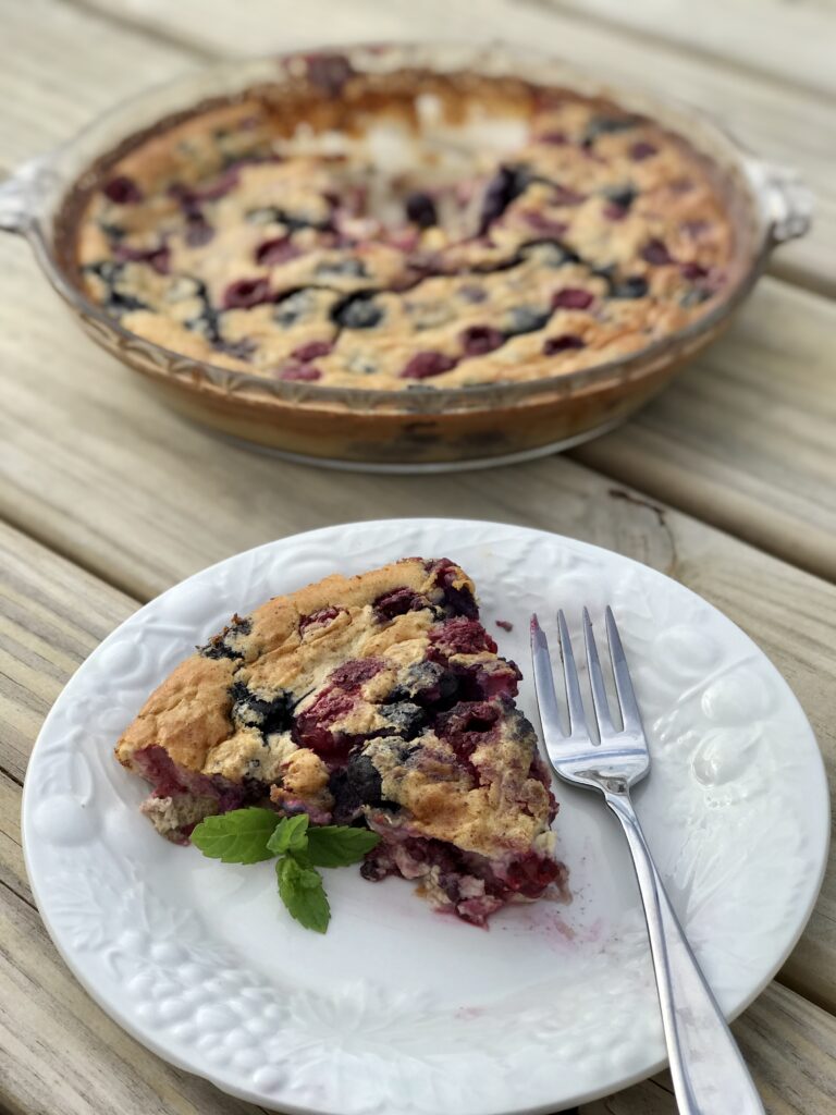slice of mixed berry clafoutis on table with fork