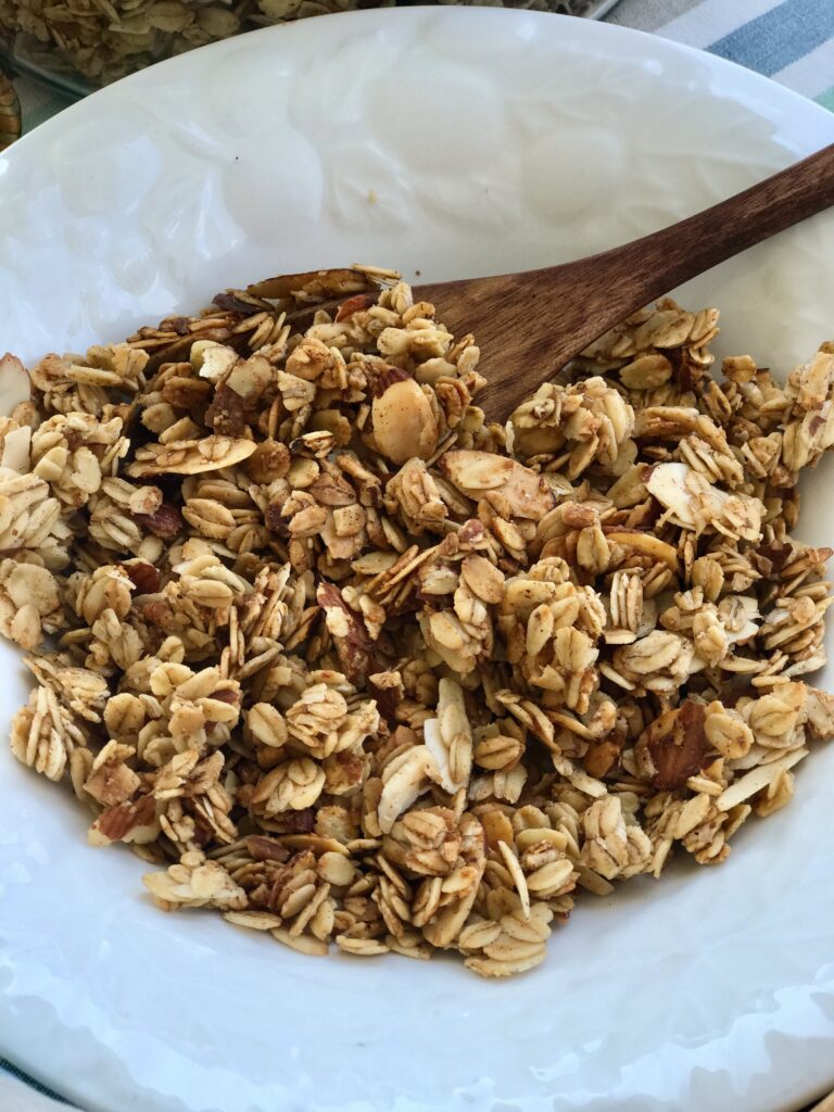 homemade granola in a white bowl with wooden spoon