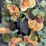 orange & eucalyptus winter wreath on a black door close up