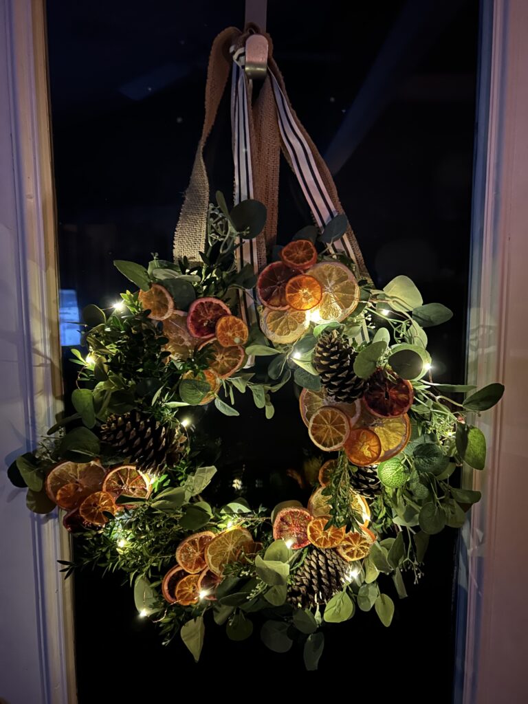 orange & eucalyptus winter wreath lit up with fairy lights