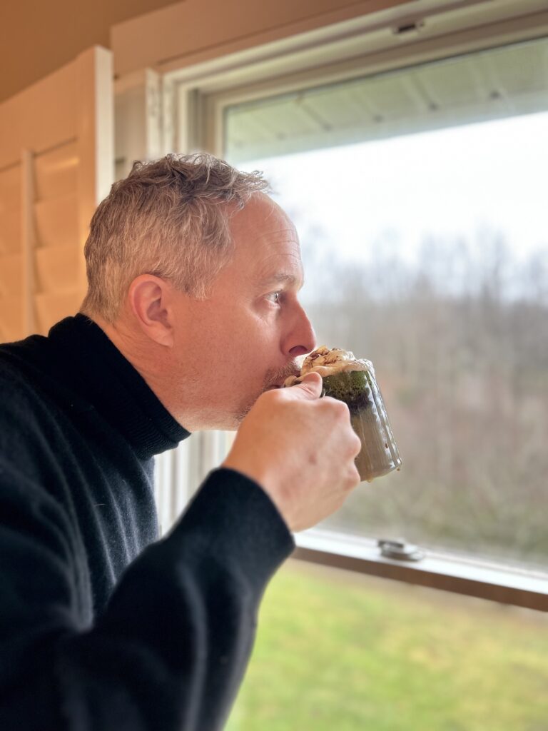 man drinking hot chocolate while looking out a window