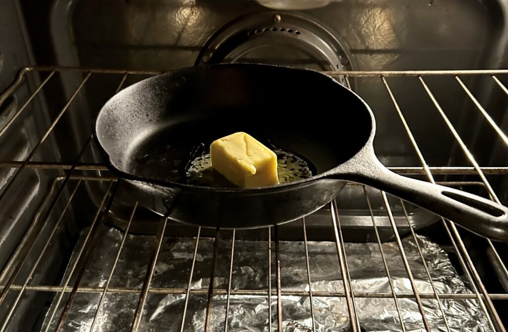 butter melting in a cast iron skillet in the oven