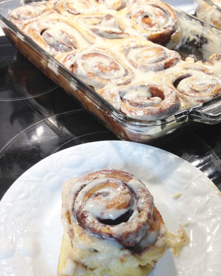 a tray of cinnamon rolls with a single cinnamon roll on the side