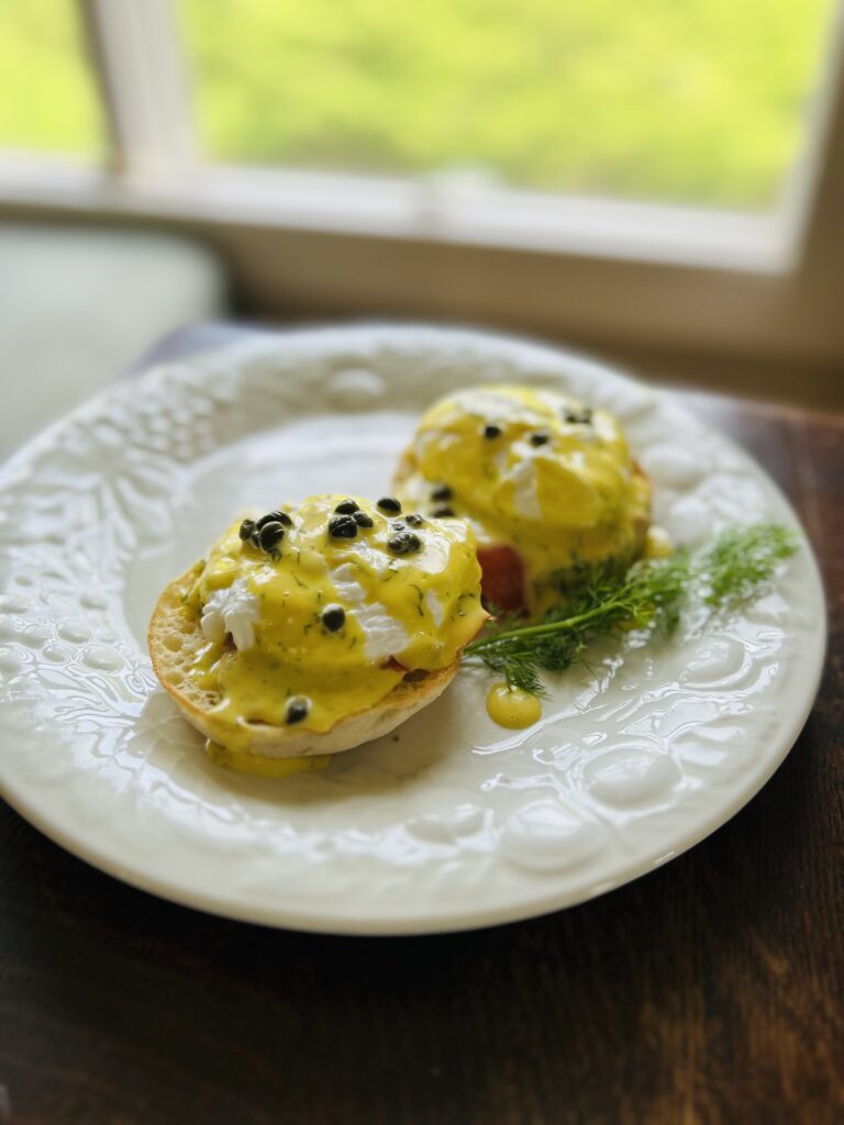 eggs Benedict with hollandaise sauce plated in front of a window
