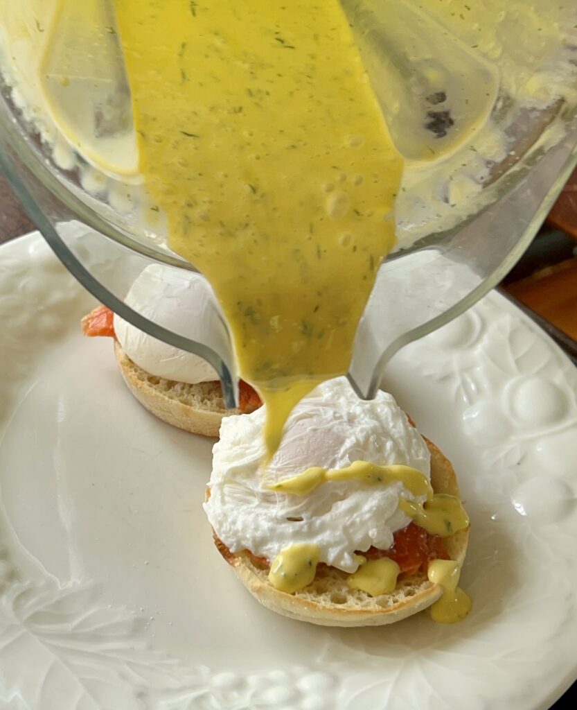 pouring hollandaise sauce onto the poached eggs