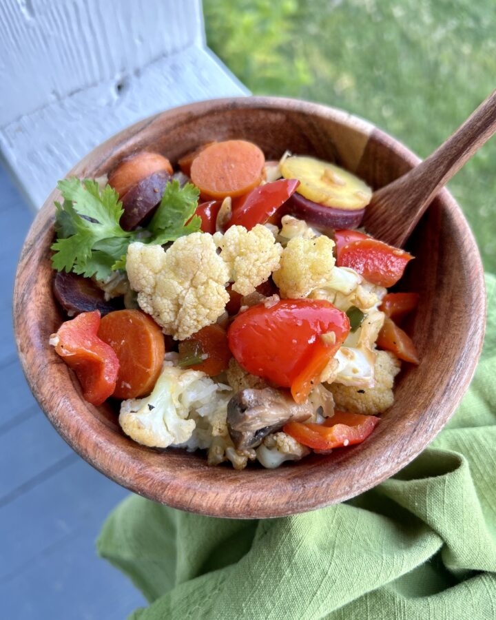 bowl of spicy veggies and coconut rice in wooden bowl with wooden spoon