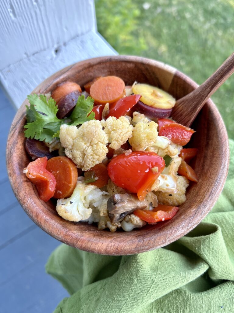 bowl of spicy veggies and coconut rice in wooden bowl with wooden spoon