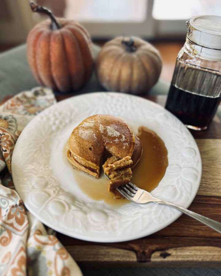 pumpkin pancakes on a white plate with pumpkins
