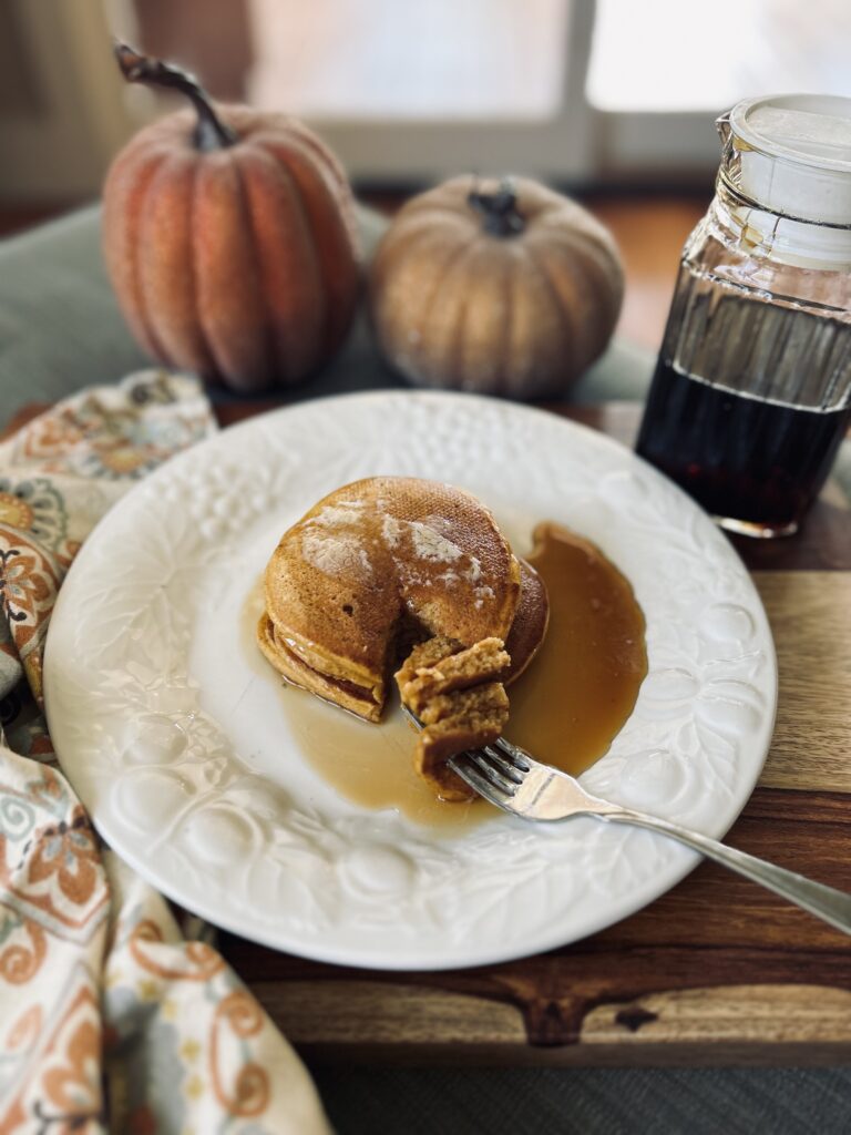 pumpkin pancakes on a white plate with pumpkins