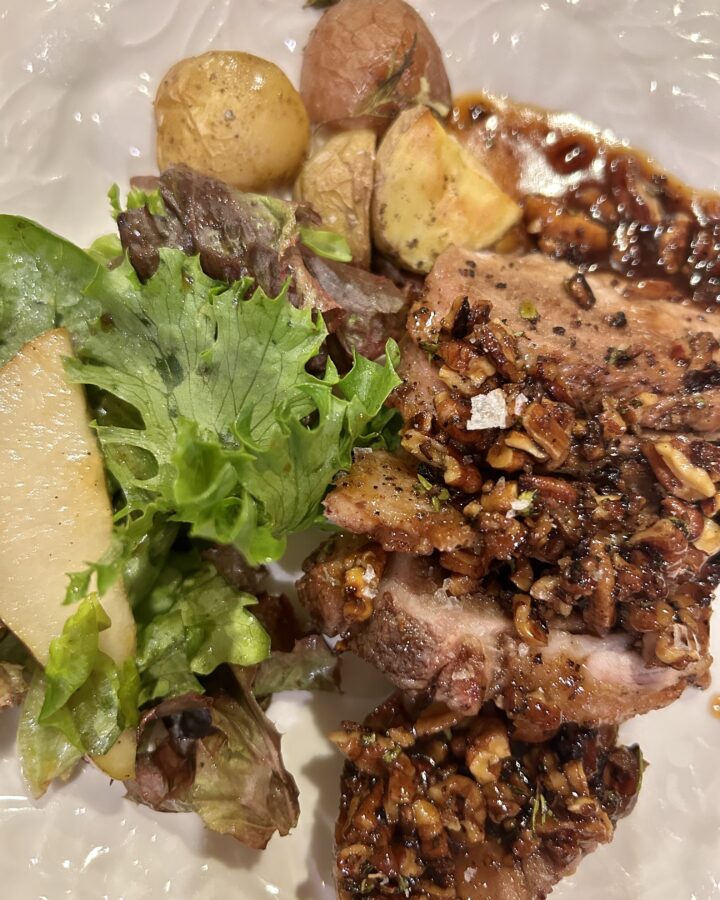 pork tenderloin with maple pecan sauce plated with roasted potatoes and a salad
